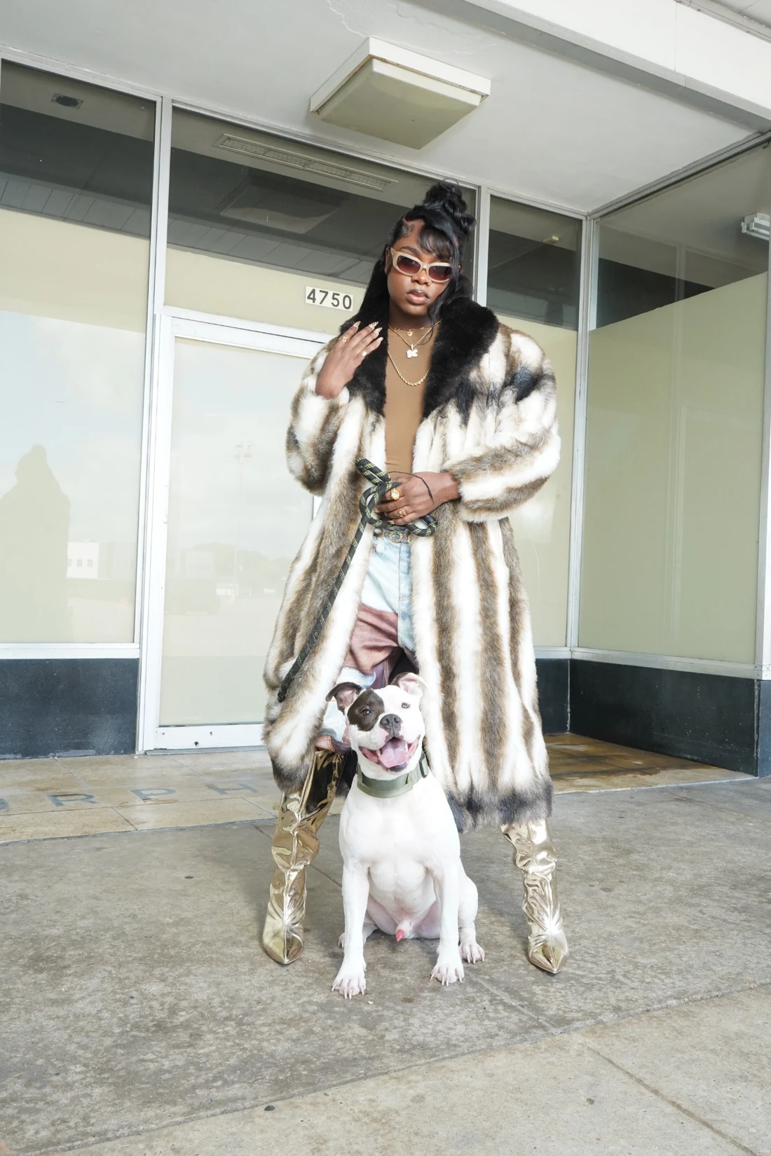 Lo-Key standing behind a white dog in a fur coat and metallic boots