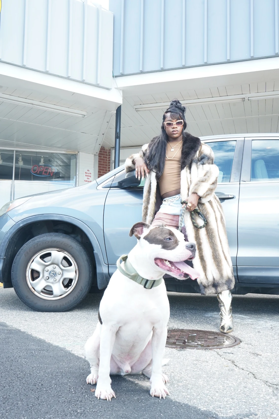 Lo-Key leaning against a vehicle with their dog in front